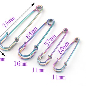 May include: Four rainbow-colored safety pins of different sizes. The pins measure 1.5 inches, 1.6 inches, 1.1 inches, and 1.1 inches in diameter. The pins are 7.5 inches, 6.4 inches, 5.7 inches, and 5 inches long.