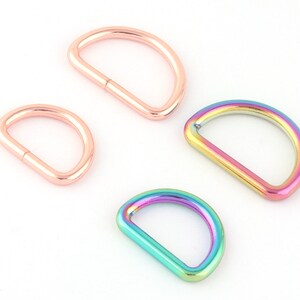 May include: Four metal D-rings in two different sizes. Two are rose gold and two are iridescent rainbow.