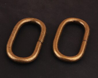 May include: Two gold-colored metal oval rings with a smooth finish. The rings are open on one side and have a slight bend on the other side.