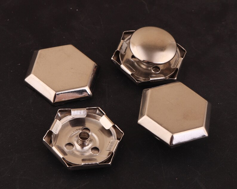 May include: Four silver-toned metal hexagonal-shaped decorative embellishments. Two of the embellishments have a raised center dome. The other two embellishments are flat.