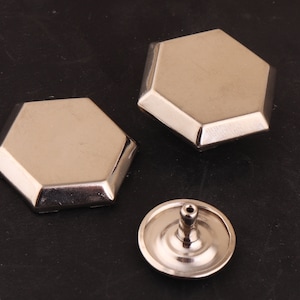 May include: Three silver metal hexagonal shaped decorative embellishments. Two are flat and one is domed.