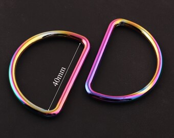 May include: Two iridescent metal D-rings, one with a 40mm diameter, the other with a larger diameter. The rings are a rainbow of colors, including pink, purple, blue, green, and yellow.