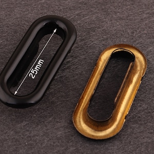 Puede incluir: Dos ojales ovalados, uno negro y otro dorado. El ojal negro tiene una abertura de 25 mm de diámetro.