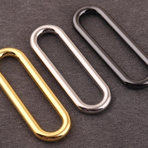 Peut inclure: Trois anneaux métalliques ovales en or, argent et noir.