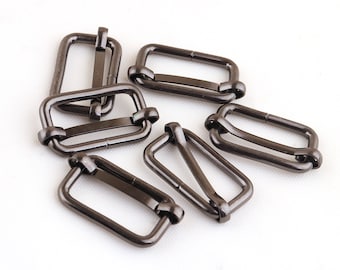 May include: Six black metal slider buckles. The buckles are rectangular with a double loop design. They are commonly used for straps, bags, and other accessories.