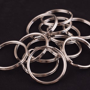 May include: A pile of silver key rings, all interlocked together. The key rings are made of metal and have a smooth, shiny finish.