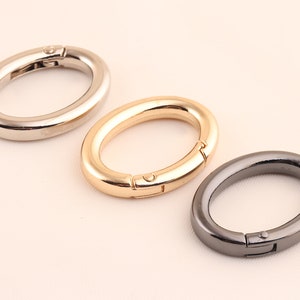 Puede incluir: Tres cierres metálicos ovalados en plata, oro y negro.