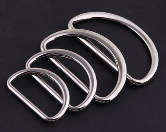 May include: Four silver metal D-rings of different sizes, stacked on top of each other.