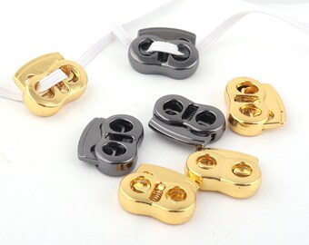 May include: Assortment of gold and black plastic toggle clasps. The clasps have two holes and are designed to be used with elastic cord or string.