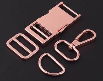 May include: A set of rose gold metal hardware for crafting projects. The set includes a buckle, a slider, a swivel hook, and a D-ring.