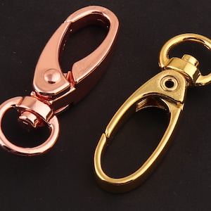 May include: Two metal keychains, one gold and one rose gold. Both keychains have a swivel hook and a loop for attaching keys.