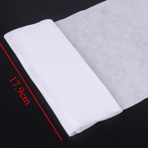 May include: A white, non-woven fabric roll, measuring 17.9 inches in length. The fabric is folded in half and is lying on a black surface.