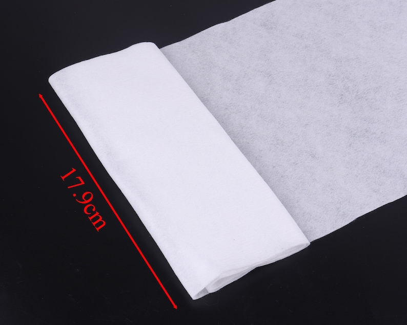 May include: A white, non-woven fabric roll, measuring 17.9 inches in length. The fabric is folded in half and is lying on a black surface.