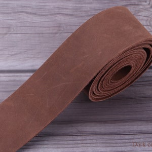 May include: A roll of dark brown leather strap, approximately 1 inch wide, on a wooden surface. The leather has a distressed, vintage look. "Dark coffee" is written in white text on the surface.