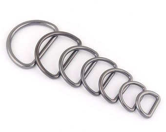 May include: A set of seven silver-toned metal D-rings of varying sizes. The rings are arranged in order of size, with the largest ring at the top and the smallest ring at the bottom.