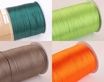 May include: Four spools of waxed cotton cord in different colors: green, light green, brown, and orange. The cord is wound around a cardboard spool.
