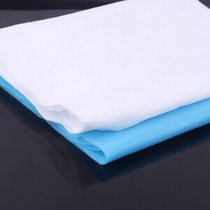 May include: A white and light blue non-woven fabric sheet. The sheet is folded in half and the white side is on top. The sheet is made of a soft, breathable material.