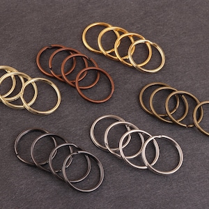 May include: Assortment of key rings in gold, silver, and bronze. The key rings are arranged in groups of three or four, with each group featuring a different color.