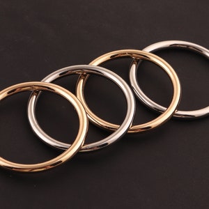 May include: Four interlocking metal rings, two silver and two gold, with a polished finish.