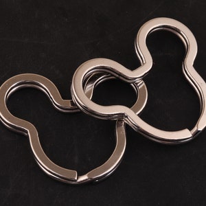 May include: Three interlocking silver metal keychains shaped like a Mickey Mouse head.
