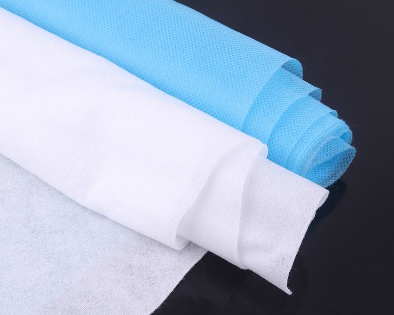 May include: Two rolls of non-woven fabric, one white and one light blue, are rolled up and stacked on top of each other. The fabric is soft and smooth, and it is perfect for a variety of craft projects.