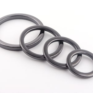 Könnte beinhalten: Vier schwarze Metallringe in verschiedenen Größen, übereinander gestapelt.
