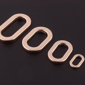 Op de afbeelding: Vier goudkleurige ovale metalen ringen in verschillende maten. De ringen zijn glad en hebben een gepolijste afwerking.