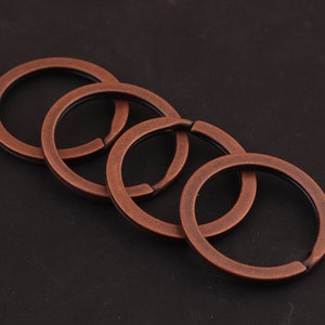 May include: Four antique copper-colored key rings linked together. The rings are smooth and have a slightly worn finish.