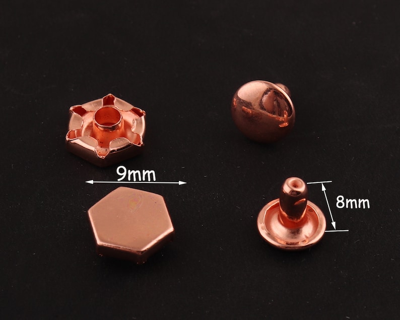 May include: Two rose gold metal rivets, one with a 9 mm diameter and the other with an 8 mm diameter. The rivets have a domed top and a flat base.