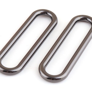 May include: Two black metal oval rings, each with a smooth, shiny finish. The rings are approximately 5 cm long and 2.5 cm wide.