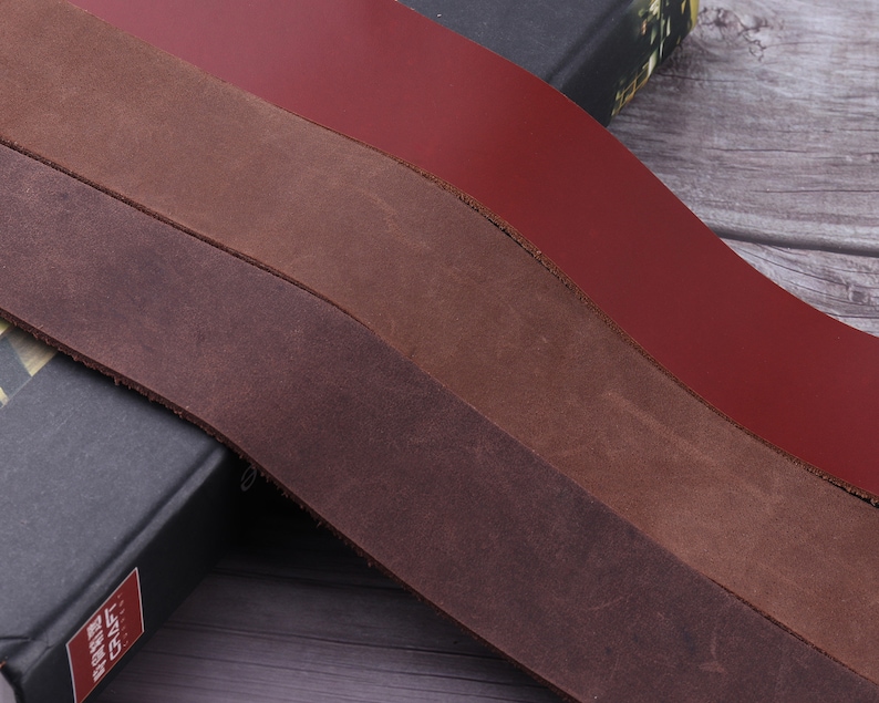 May include: Three strips of leather in different shades of brown and red. The leather is smooth and has a natural grain.