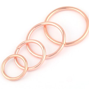 May include: Set of four rose gold hoop earrings in different sizes. The hoops are smooth and have a polished finish.