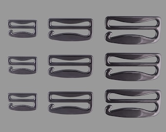 May include: Nine black metal bra strap adjusters in various sizes. The adjusters have two loops and a hook.