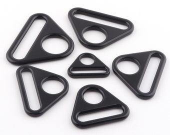 May include: Six black triangle-shaped metal rings with a small hole in the center and a larger oval opening. The rings are of varying sizes.