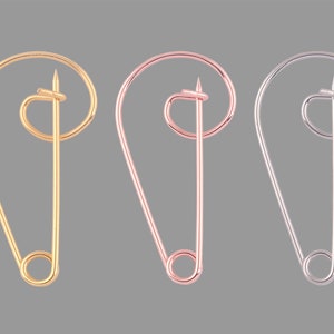Può includere: Tre spille da balia di diversi colori: oro, oro rosa e argento. Le spille sono tutte della stessa dimensione e forma, con una testa arrotondata e una punta affilata.