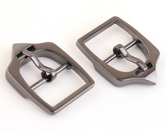 May include: Two silver-toned metal belt buckles. The buckles are rectangular with a pointed end and a single prong closure.