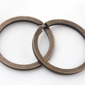 May include: Two antique gold-toned metal key rings linked together. The rings are round and have a smooth, slightly textured surface.