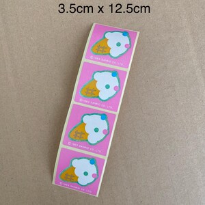 May include: A sheet of four pink stickers with an ice cream cone design. Each sticker features a white ice cream cone with a pink and blue swirl on top. The text "1983 SANRIO CO. LTD." is printed on each sticker.