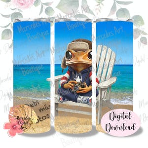 Puede incluir: Un vaso con una rana con sombrero y sudadera con capucha, sosteniendo una cámara y sentado en una silla de playa. El fondo muestra una escena de playa con agua y cielo azules. El texto incluye "Mercedes Boutique" y "Digital Download."
