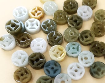May include: A collection of round jade beads with a carved design. The beads are in various shades of green, white, and brown.