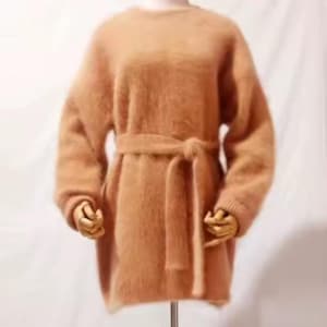 Può includere: Un abito a maglione a maniche lunghe, soffice e marrone chiaro, caratterizzato da uno scollo rotondo e una cintura da annodare in vita. Il capo presenta un aspetto morbido e testurizzato con polsini a coste e un orlo dritto.
