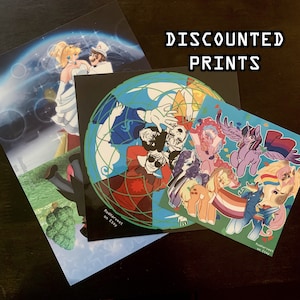 May include: Three different prints featuring various cartoon characters. The first print is a blue and green illustration of a group of people standing on a globe. The second print is a blue and pink illustration of a group of cartoon horses. The third print is a blue and white illustration of a cartoon princess and a cartoon man. The prints are all available for purchase on Etsy.