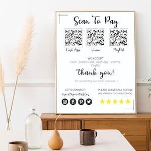 May include: White sign with the text "Scan To Pay" and three QR codes labeled "Cash App", "Venmo", and "PayPal". The sign also includes the text "We Accept", "Cash, Credit Card, Cash App, Venmo, PayPal", "Thank you!" and "For supporting our small business". The sign also includes the text "Let's Connect!" with a social media icon for Instagram, Facebook, Pinterest, and Twitter. The sign also includes the text "Please leave us a review (We appreciate your feedback)" with five gold stars.