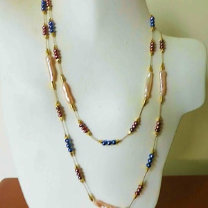 May include: A double-strand necklace with gold chain, pink and white baroque pearls, and blue and burgundy beads.