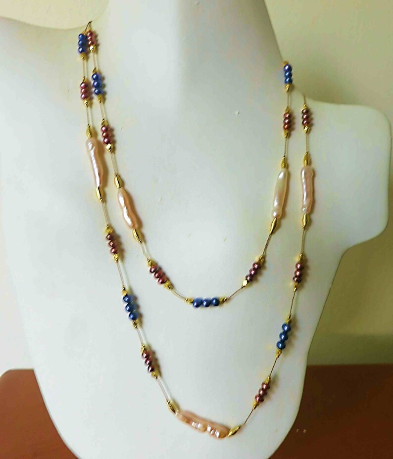 May include: A double-strand necklace with gold chain, pink and white baroque pearls, and blue and burgundy beads.