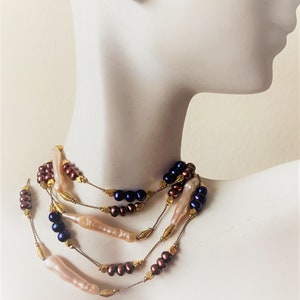May include: A multi-strand necklace with brown, blue, and cream colored beads. The necklace is made of pearls and gold-toned beads.