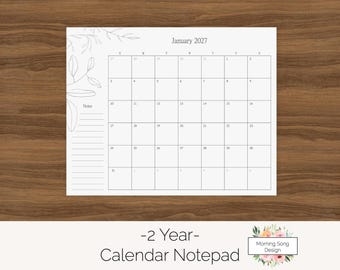 Könnte beinhalten: Ein weißer Kalender-Notizblock aus Papier für Januar 2027 mit einem Raster für die nummerierten Tage, einem Notizbereich auf der linken Seite und feinen grauen Linienzeichnungen botanischer Blätter oben links. Der Text lautet January 2027.