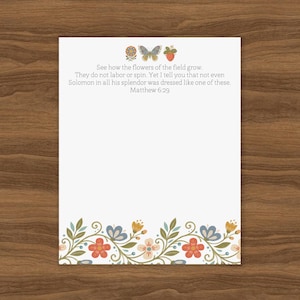 Puede incluir: Una hoja de papel de carta rectangular blanca con un borde floral en la parte inferior con flores rojas, azules y naranjas y hojas verdes. En la parte superior, un icono de mariposa, flor y fresa aparece sobre el texto: See how the flowers of the field grow. They do not labor or spin. Yet I tell you that not even Solomon in all his splendor was dressed like one of these. Matthew 6:29.