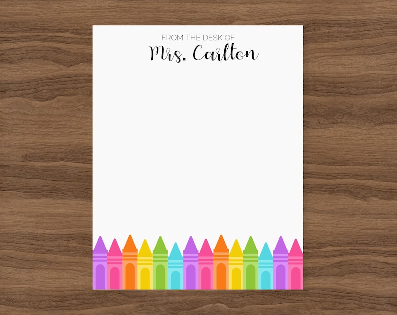 May include: White notepad with the text "From the desk of Mrs. Carlton" at the top. The bottom of the notepad has a row of colorful crayons.