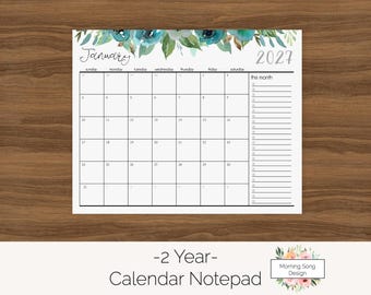 Könnte beinhalten: Ein Kalender-Notizblock für Januar 2027 mit einem Aquarell-Blumenrand in Blaugrün- und Grüntönen am oberen Rand. Das Raster enthält Wochentage, nummerierte Daten und einen vertikalen Listenbereich auf der rechten Seite mit der Beschriftung this month.